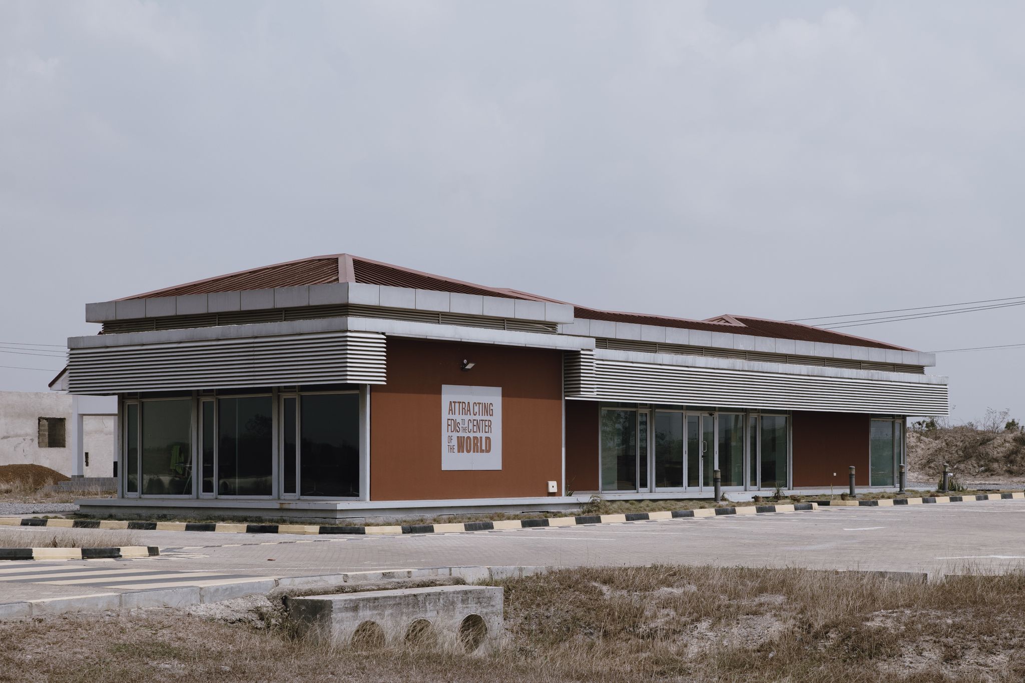 A modern commercial building with reflective glass in a deserted outdoor area.