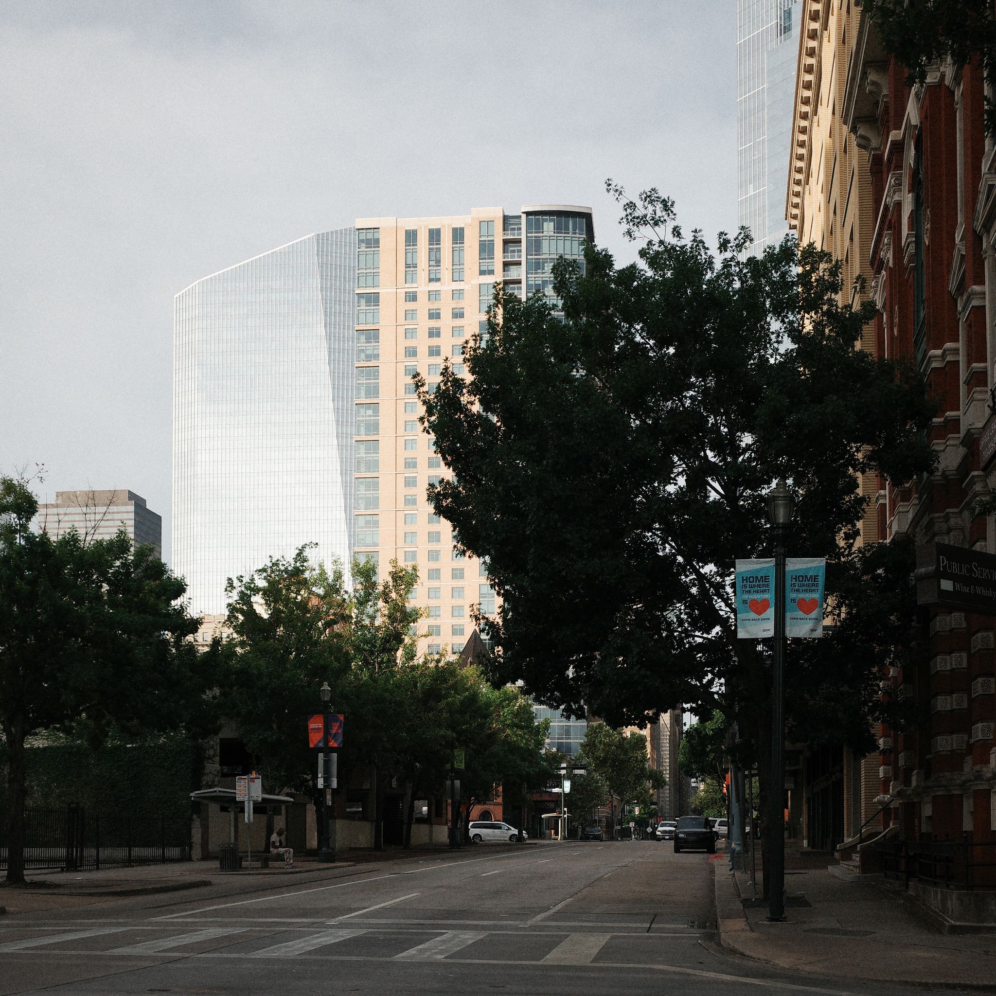 View of downtown with modern skyscrapers and lush greenery, capturing city life.